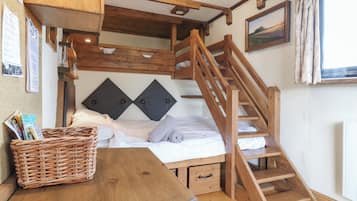 A cozy room with a wooden bunk bed, a wooden table with a basket, and a staircase.