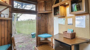 A compact kitchen with wooden cabinets, a built-in fridge, and a small dining area with a bench. - Daisy (Woodbridge)