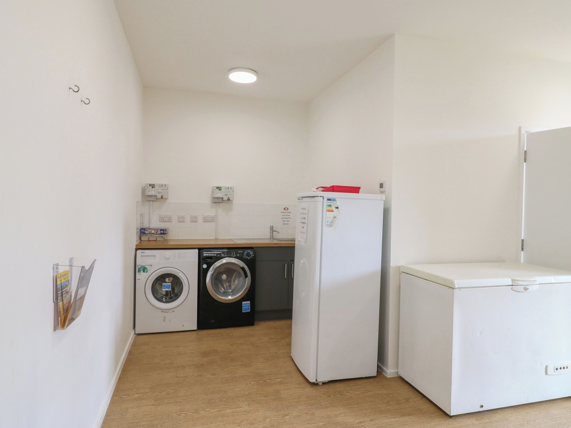 Een kleine keuken met een wasmachine, een koelkast en een magnetron.
