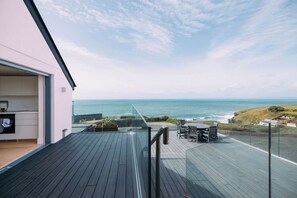 Uma casa moderna com terraço de madeira com vista para o oceano.