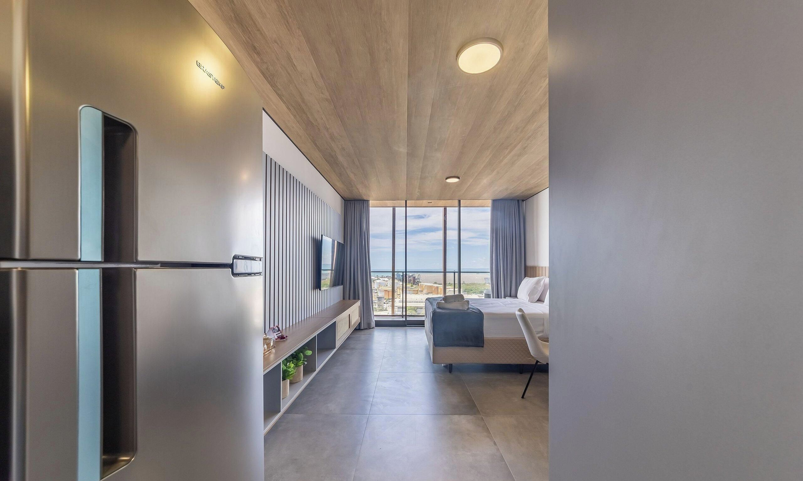Una habitación de hotel moderna con un ventanal grande, un televisor de pantalla plana, un sofá y una cama.