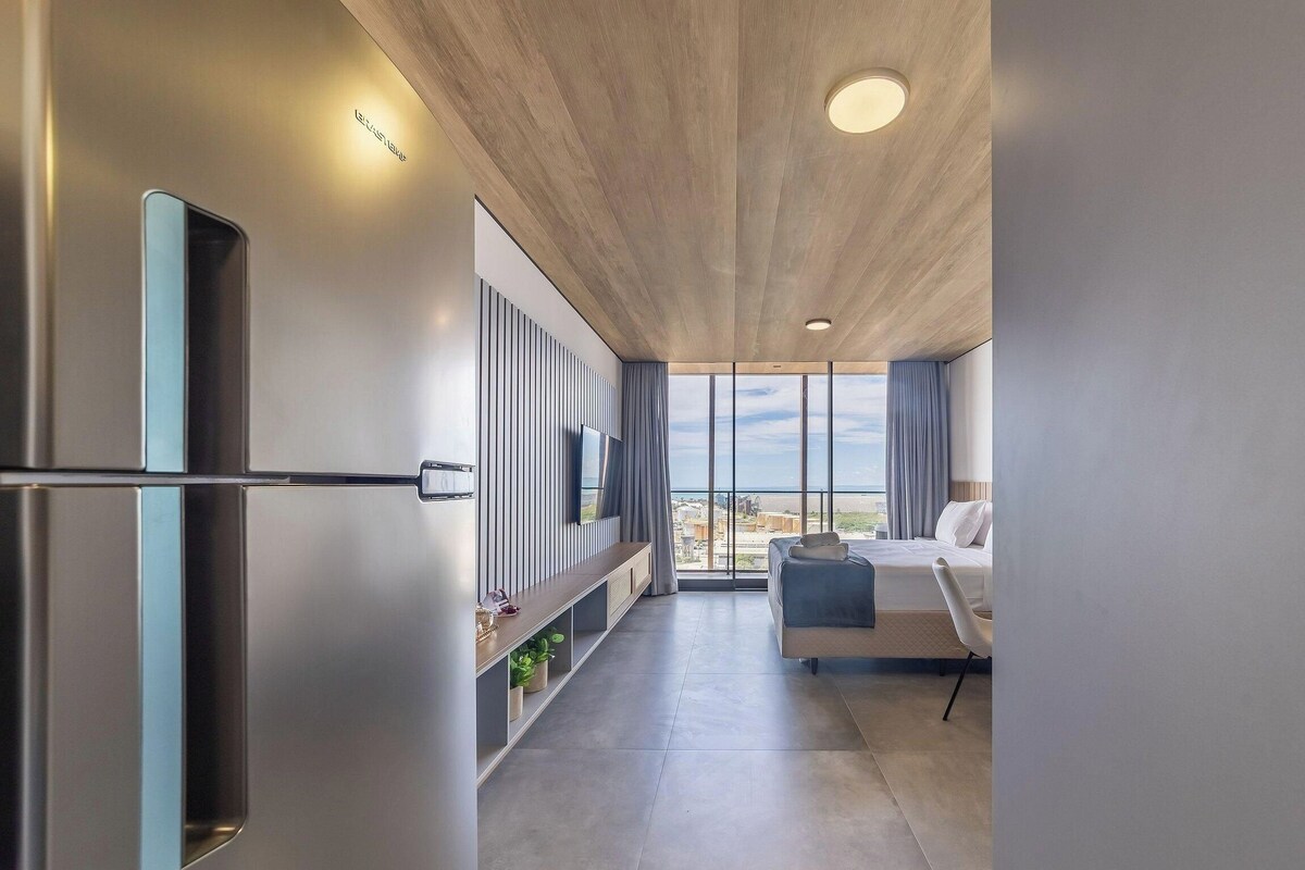 Una habitación de hotel moderna con un ventanal grande, un televisor de pantalla plana, un sofá y una cama.