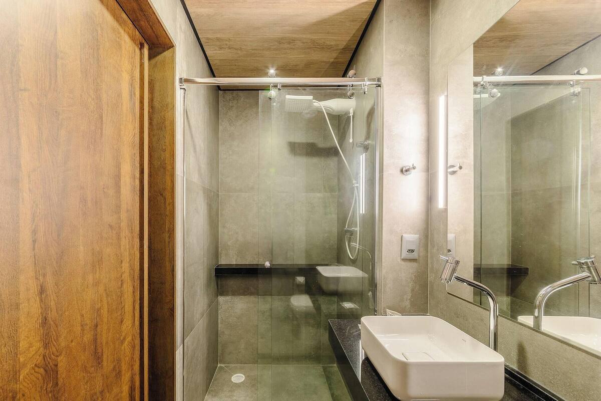 A modern bathroom with a glass-enclosed shower, a white sink, and a large mirror.