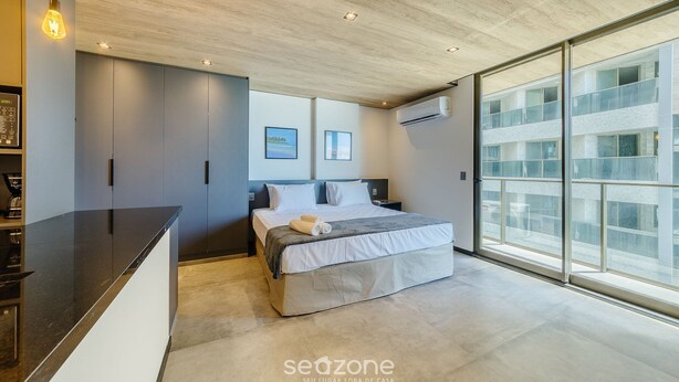 Une chambre moderne dotée d’un grand lit, d’un bureau intégré et d’une grande fenêtre donnant sur la ville.