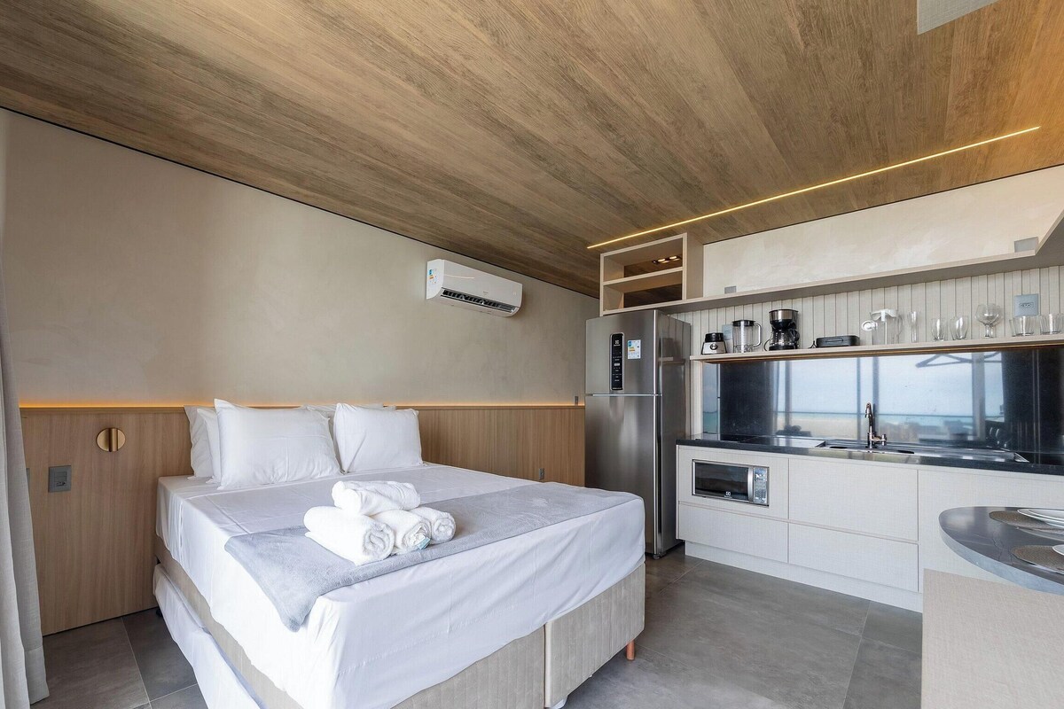 Een moderne hotelkamer met een bed, een geïntegreerde keuken en een airconditioning.