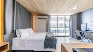 A modern hotel room with a large bed, a desk, and a view of the city. - Nwts - Studios With Side sea View in Maceio II (Maceió)