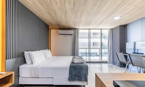 Een moderne hotelkamer met een bed, een bureau en een groot raam met uitzicht op de stad.