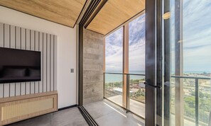 Un interno moderno con una TV a schermo piatto montata a parete, un tavolino consolle in legno e un'ampia finestra con vista sulla città.