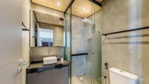 A modern bathroom with a glass shower enclosure, a sink with a mirror above, and a toilet. - Nwts - Studios With Side sea View in Maceio II (Maceió)