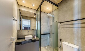 Een moderne badkamer met een douchecabine van glas, een wit toilet en een wastafelmeubel met een wastafel.