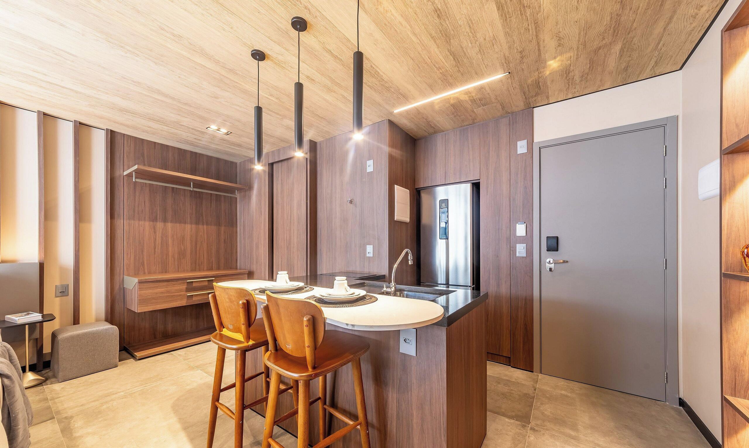 Une cuisine moderne dotée d’un îlot central, de meubles en bois et de luminaires suspendus.