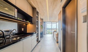 A modern kitchen with a built-in stove, a sink, and a window overlooking a cityscape. - Nwts - Studios With Side sea View in Maceio II (Maceió)
