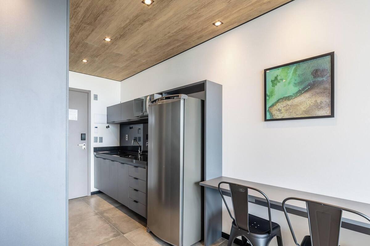 A modern kitchen with a stainless steel refrigerator, a dining area with a table and chairs, and a painting on the wall.