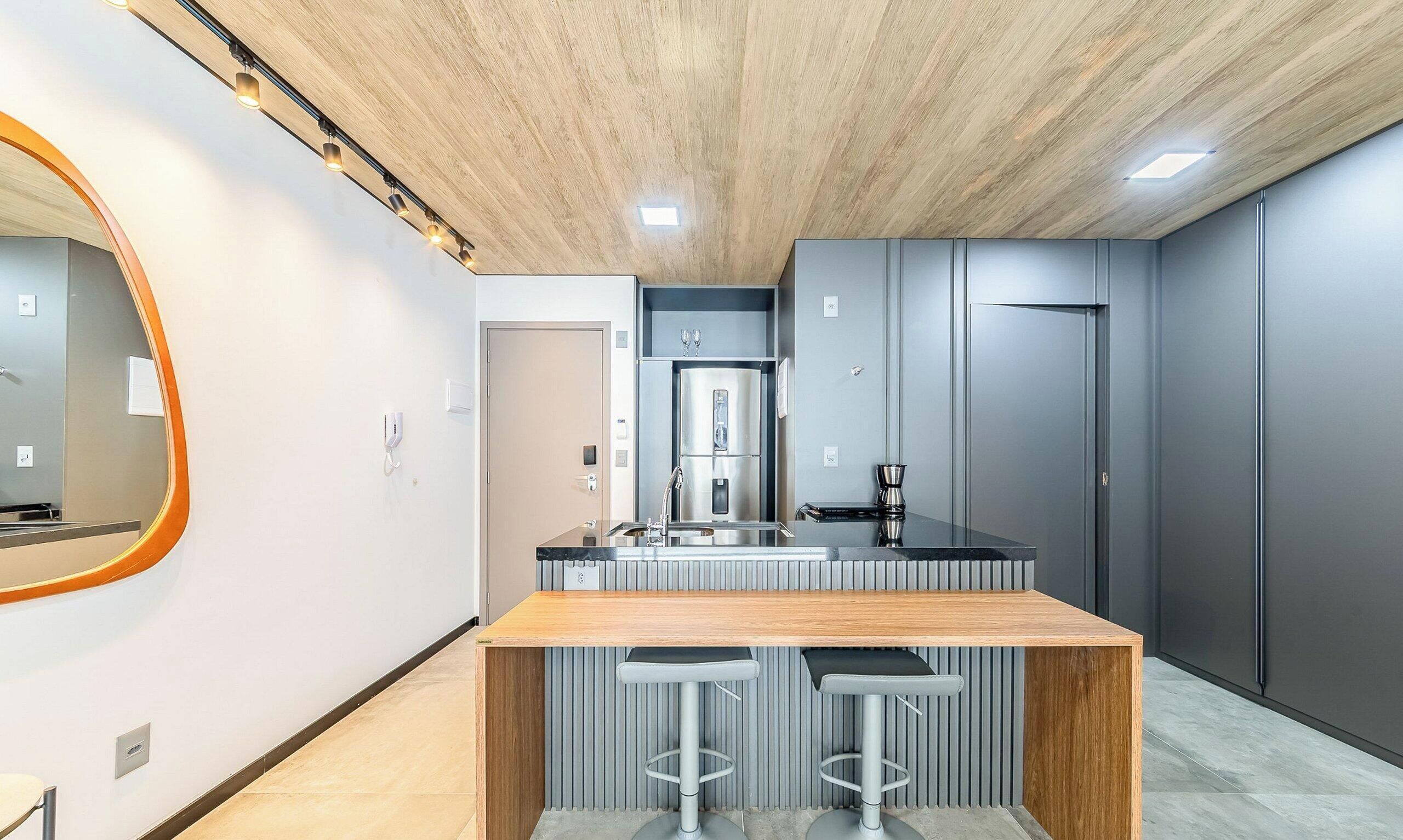 A modern kitchen with a wooden island, grey cabinetry, and a built-in oven.
