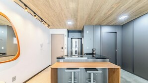 Une cuisine moderne avec un îlot central en bois, des meubles de rangement gris et un four encastré.