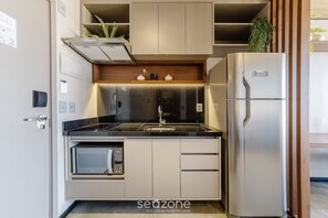 Una cucina compatta con forno integrato, frigorifero in acciaio inossidabile e piano di lavoro in legno.