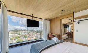 A hotel room with a large window offering a city view, a bed, a desk, and a chair. - Nwts - Studios With Side sea View in Maceio II (Maceió)