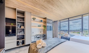 A modern bedroom with a large window, a bed, a desk, and built-in storage. - Nwts - Studios With Side sea View in Maceio II (Maceió)