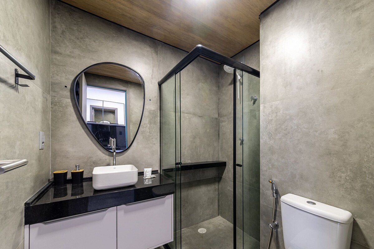 A bathroom with a glass-enclosed shower, a sink with a mirror, and a toilet.