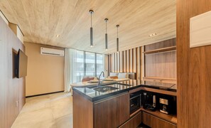 Een moderne keuken met een centraal eiland, hangende verlichting en inbouwapparatuur.