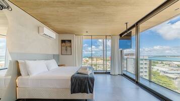 Habitación de hotel moderna con una cama grande, vistas a la ciudad y un balcón.
