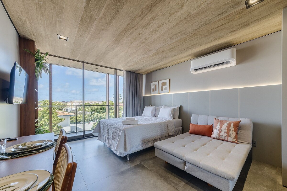 Een moderne hotelkamer met een groot bed, een zithoek, een eethoek en uitzicht op de stad.