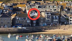 A coastal town with a harbor filled with boats, a large naval ship in the background, and a church on a hill. - Sleeps 6 guests  in 3 bedrooms (St Ives, Saint Ives)