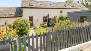 A two-story house with a white exterior, a wooden deck, and a fenced yard. - 3 The Barn (Haverfordwest)