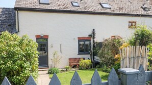 A house with a white exterior, a tiled roof, and a wooden fence in the foreground. - 3 The Barn (Haverfordwest)