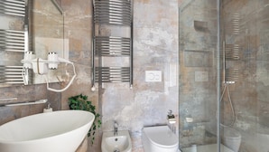 A modern bathroom with a freestanding bathtub, a bidet, a glass-enclosed shower, and a towel rack.