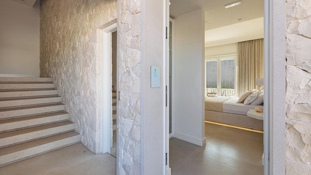 A staircase leading to a bedroom with a stone wall and a bed with a view.