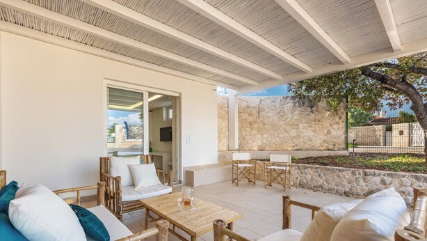 Eine Außenpatio mit Holzmöbeln, einer Steinmauer und Blick auf die Umgebung.