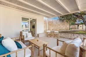 Une terrasse extérieure avec des meubles en bois, un mur en pierre et une vue sur les environs.