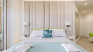 Ein Hotelzimmer mit einem Bett, zwei Nachttischlampen, einem Nachttisch, einem Spiegel und einem grünen Sessel.