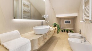 Un baño moderno con un lavamanos ovalado grande, una bañera independiente y un espejo sobre el lavamanos.