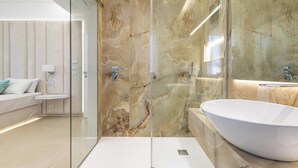 Une salle de bain moderne avec une douche à parois de verre, un grand lavabo blanc et des murs en marbre.