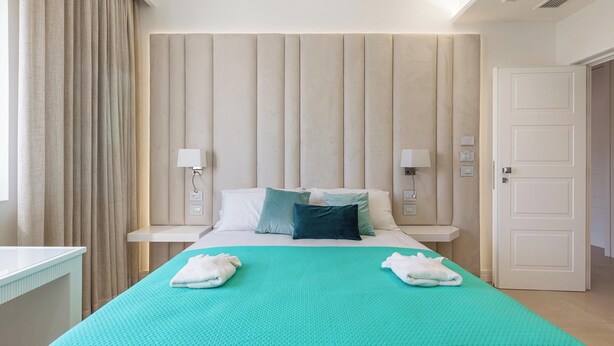 Une chambre d’hôtel avec un lit, deux tables de chevet, une porte et une fenêtre avec des rideaux.