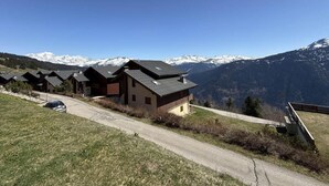 En række chalet-lignende bygninger med krystalklar udsigt til sneklædte bjerge i baggrunden.