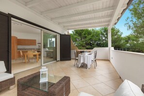 A covered outdoor patio with a dining table and chairs, a wicker sofa, and a glass table. - Villa Madonnina - Comfort Plus by BarbarHouse (Campomarino)