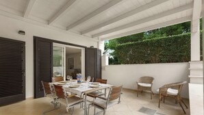 A covered patio with a dining table, chairs, and a view of greenery. - Villa Madonnina - Trilo Comfort by BarbarHouse (Campomarino)