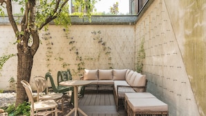 Una terraza de madera con un sofá, sillas y una mesa de mimbre.