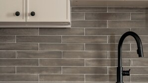 Una cocina con armarios blancos, un grifo negro y un salpicadero de azulejos.