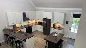 Eine moderne Küche mit weißen Schränken, einer zentralen Kochinsel und einer dunklen Holz Arbeitsplatte.