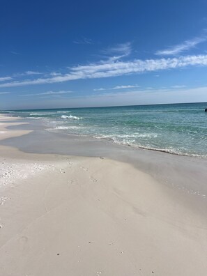 Une plage avec une eau d’un bleu limpide et un rivage sablonneux.
