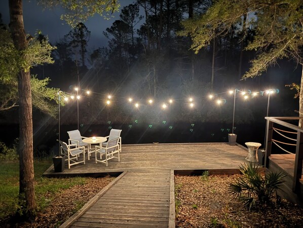 An outdoor deck with string lights, a round table, and chairs.
