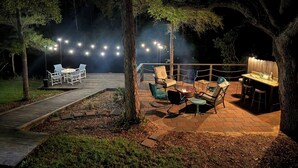 Un espace extérieur aménagé en terrasse, avec un sol en bois, des meubles de jardin et des guirlandes lumineuses.