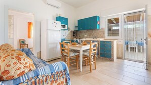 Un espacio habitable compacto con kitchenette, comedor y sofá con ropa de cama estampada.