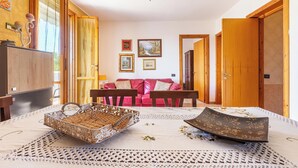 Una habitación acogedora con un ventilador de techo de madera, un sofá rojo y una mesa de comedor con mantel individual tejido.