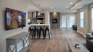 A modern kitchen with a central island, bar stools, and a large painting on the wall. - Lauralee’s Legacy House-Minutes to Cedar Point (Sandusky)