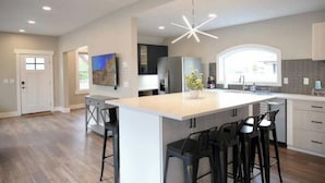 A modern kitchen with a large island, bar stools, and recessed lighting. - Lauralee’s Legacy House-Minutes to Cedar Point (Sandusky)